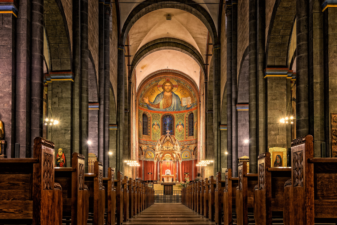 Inside a church with pews, three small children laying down, kids sitting in a circle with a man, a judge writing down in a book on a desk.